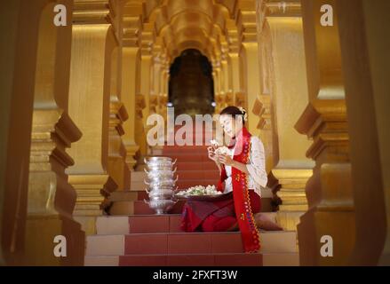 Myanmar women holding flowers at a temple. Southeast Asian young girls with burmese traditional dress visiting a Buddihist temple Stock Photo