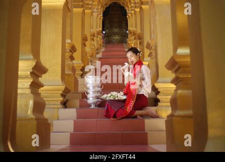 Myanmar women holding flowers at a temple. Southeast Asian young girls with burmese traditional dress visiting a Buddihist temple Stock Photo