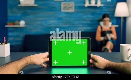 Point of view of business man hands holding tablet computer with mock up green screen chroma key display standing on desk table. Caucasian male using isolated device for digital advertising Stock Photo