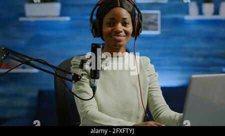 Portrait of african smiling blogger looking at camera before starting live video from home studio podcast. Content creator vlogger woman recording brodcast streaming online content for social media Stock Photo