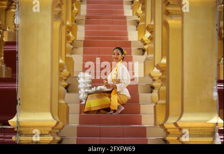 Myanmar women holding flowers at a temple. Southeast Asian young girls with burmese traditional dress visiting a Buddihist temple Stock Photo