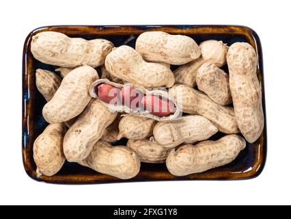 top view of unpeeled peanuts with peeled seeds in bowl cutout on white background Stock Photo