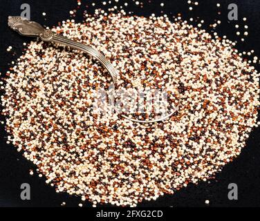 tablespoon in mix of quinoa seeds on black plate Stock Photo