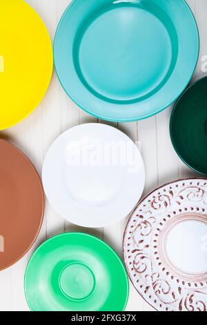 Empty multicolored plates on a wooden background, top view. Stock Photo