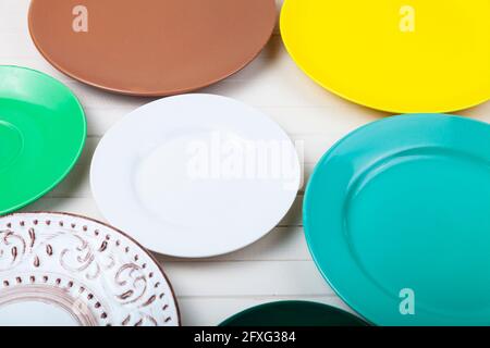 Empty multicolored plates on a wooden background, top view. Stock Photo