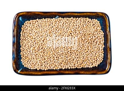 top view of white mustard seeds on rectangular plate cutout on white background