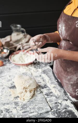 Close-up of baker with flour on her hands kneading a dough in the kitchen Stock Photo
