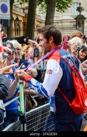 Mark Hunter showing the public his rowing silver medal as Team GB Olympians leaving Buckingham Palace after the victory parade. London 2012 Olympics. Stock Photo