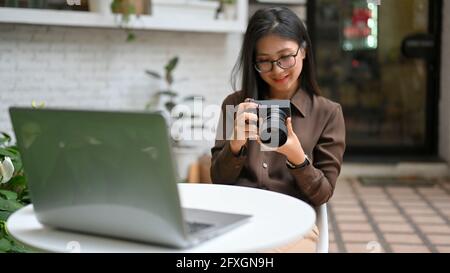 Portrait of happy female photographer smiling and checking photo on digital camera Stock Photo