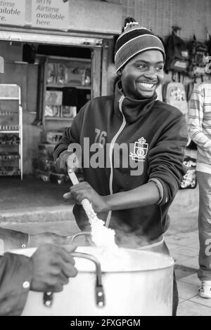 JOHANNESBURG, SOUTH AFRICA - Jan 05, 2021: Johannesburg, South Africa, July 12, 2009, Young African man cooking Mielie Pap maize porridge on side stre Stock Photo