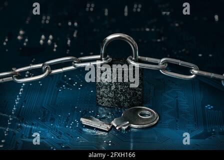 locked padlock, chain and broken key on computer circuit board Stock Photo