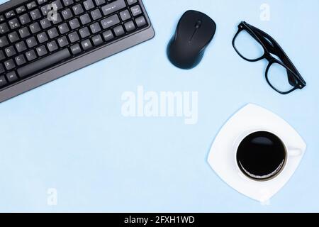 Workspace minimal flat lay. Keyboard with computer mouse, glasses, cup of coffee on office desk. Copy space Stock Photo