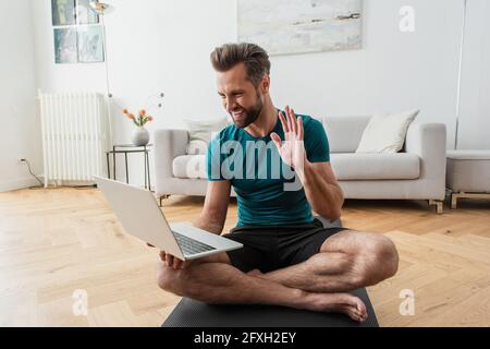 happy man having video call on laptop while practicing yoga at home Stock Photo