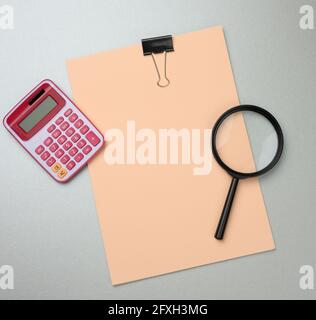 pink calculator, folder with blank  sheets and black magnifier on a gray background. Banner for business, top view Stock Photo