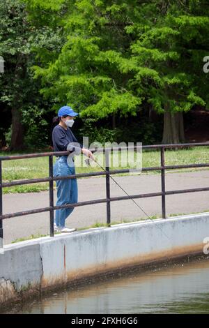 A woman fishing at the lake in Kissena Park, Flushing, Queens, New York City. Stock Photo