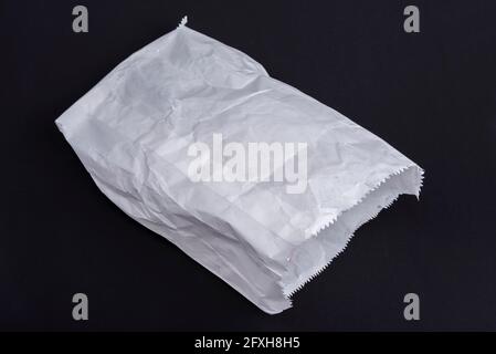 Used crumpled white paper bag on a black Stock Photo
