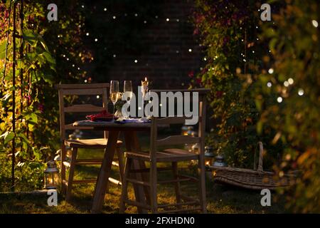 Champagne and red currants on idyllic summer garden table at sunset Stock Photo