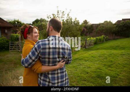 Happy affectionate couple hugging in idyllic cottage garden Stock Photo