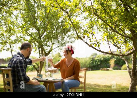 Happy couple toasting water glasses at table in sunny summer garden Stock Photo