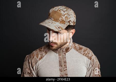 Close up of a handsome pensive young military man in uniform thinking isolated over black background Stock Photo
