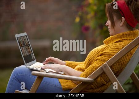 Woman using laptop in lawn chair Stock Photo