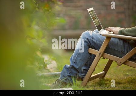 Man using laptop in lawn chair in garden Stock Photo