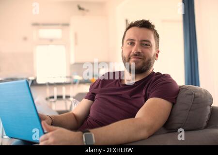 Portrait confident man working from home at laptop Stock Photo
