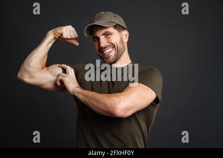 Strong healthy military man showing biceps isolated over black wall Stock Photo