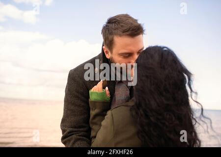 Affectionate couple kissing on ocean beach Stock Photo