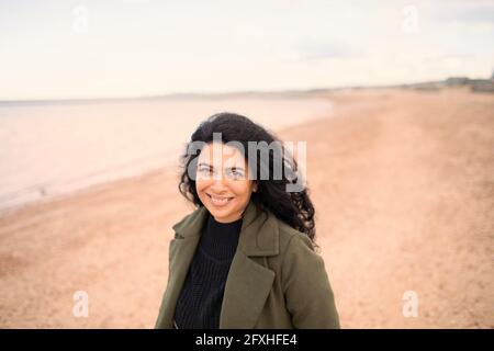 Portrait happy beautiful woman on winter ocean beach Stock Photo