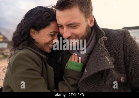 Happy affectionate couple in winter coats hugging Stock Photo