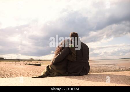 Serene affectionate couple hugging on sunny tranquil winter beach Stock Photo