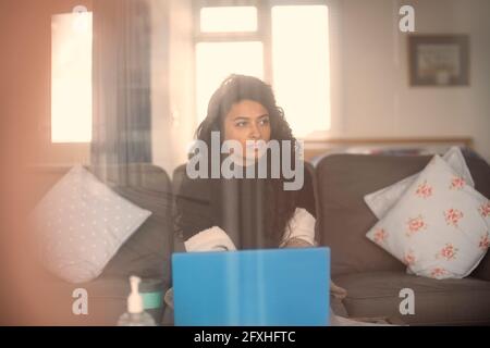 Woman with headphones working from home at laptop on sofa Stock Photo