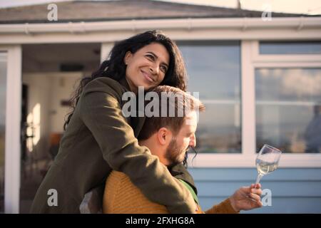 Happy couple hugging and drinking wine on patio Stock Photo