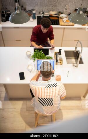 Gay male couple working from home at laptop and digital tablet Stock Photo