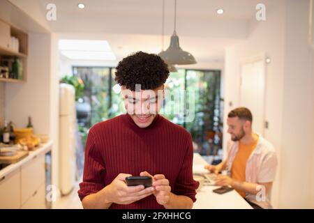 Young man using smart phone in kitchen Stock Photo
