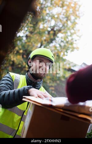 Friendly delivery man in helmet delivering packages at door Stock Photo