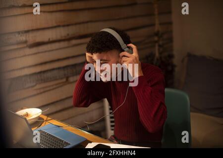 Happy young man with headphones working from home at laptop Stock Photo