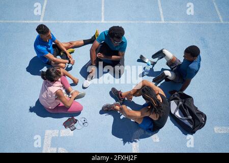 Young athletes talking on sunny blue sports track Stock Photo
