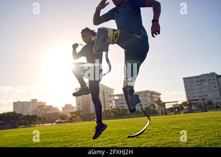 Coach and young male amputee athlete training in sunny urban park Stock Photo