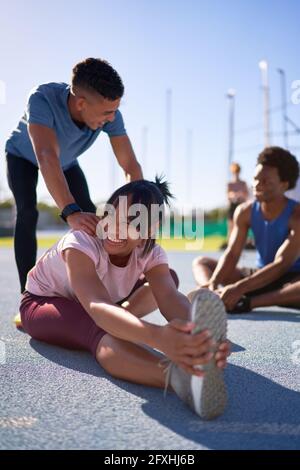 Happy young runners stretching on sunny sports track Stock Photo