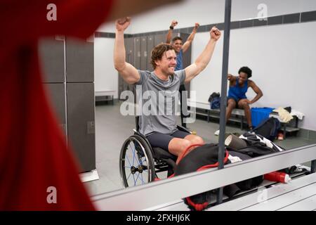Confident happy wheelchair athlete cheering in locker room mirror Stock Photo