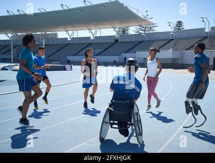Diverse athletes warming up on sunny blue sports track Stock Photo