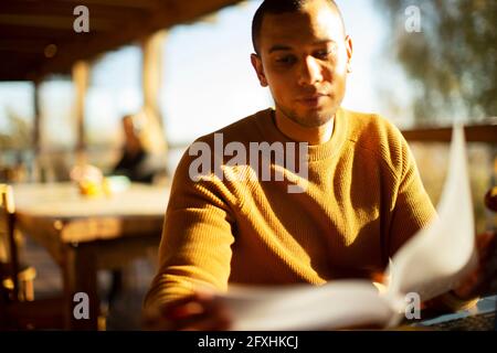 Businessman reviewing paperwork in sunny cafe Stock Photo
