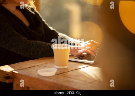 Woman with coffee working at laptop on cafe table Stock Photo