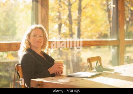 Portrait confident businesswoman with coffee working in autumn cafe Stock Photo
