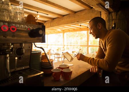 Male cafe owner using digital tablet behind counter Stock Photo