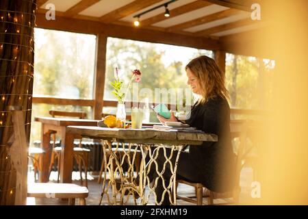 Female small business owner working at table in cafe Stock Photo