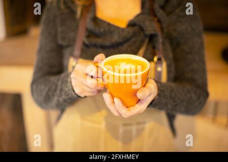 Close up female barista holding cappuccino with heart foam Stock Photo
