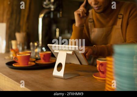 Male barista using digital tablet at cafe counter Stock Photo